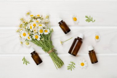 Ahşap zemin üzerinde gerekli yağı bulunan küçük bir buket papatya çiçeği.