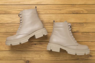 Ahşap arka planda bej renkli moda botlar, üst manzara.