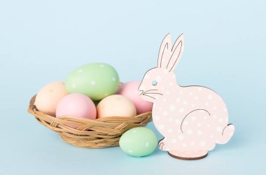 Paskalya yumurtalı sepet ve arka planda tavşan.