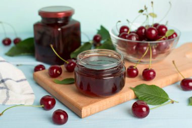 Ahşap masada ev yapımı kiraz reçelli kavanoz.