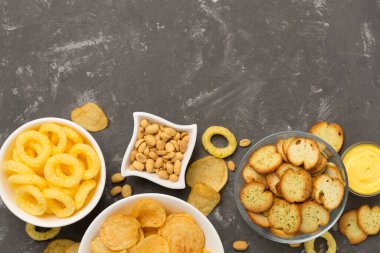 Beton arka planda farklı lezzetli atıştırmalıklar, üst görünüm