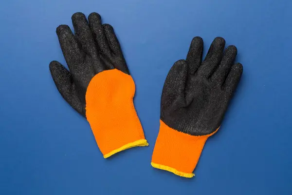 Garden gloves on color background, top view