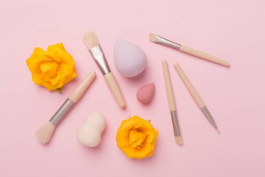 Renk arkaplanında makyaj fırçaları ve süngerler, üst görünüm