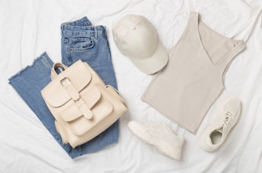 Havalı bahar kıyafetleri ve beyaz çarşaf üzerinde çiçekleri ile düz yatıyordu