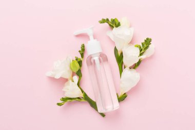 Renkli arka planda frezya çiçekleri olan kozmetik şişesi, üst görünüm