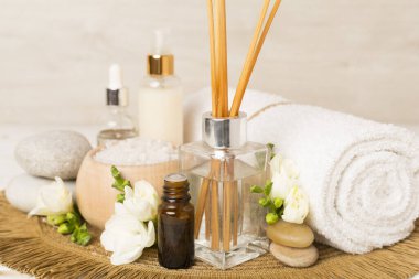 Tahta masa üzerinde frezya çiçeği ve aroma yayıcı içeren spa kompozisyonu