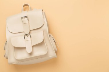 Renkli arka planda bej renkli sırt çantası, üst görünüm.