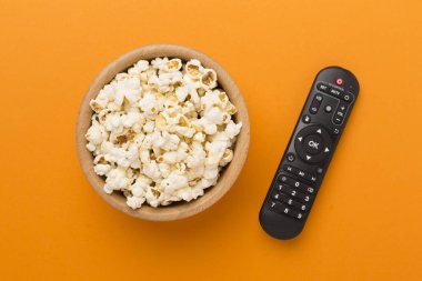 Patlamış mısır ve televizyon uzaktan kumandası renk arkaplanında