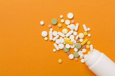 Farklı ilaç ve kapsüllere sahip kavanoz. Renkli arka plan, üst görünüm.