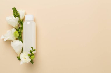 Renkli arka planda frezya çiçekleri olan kozmetik şişesi, üst görünüm