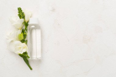 Beton arka planda çiçekli kozmetik şişesi, üst görünüm