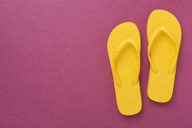 Renkli arka planda parlak sarı parmak arası terlikler, üst manzara. Yaz konsepti