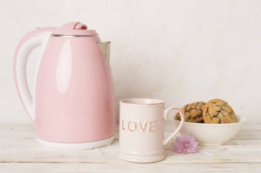 Masada çay ve tatlı ile pembe elektrikli çaydanlık.