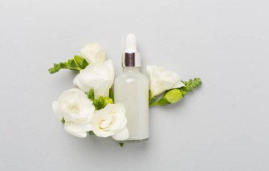 Renkli arka planda frezya çiçekleri olan kozmetik şişesi, üst görünüm