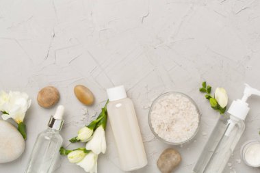 Beton zemin üzerinde spa ürünleri ve çiçeklerle yatıyordu