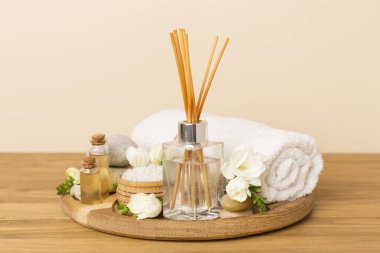 Tahta masa üzerinde frezya çiçeği ve aroma yayıcı içeren spa kompozisyonu