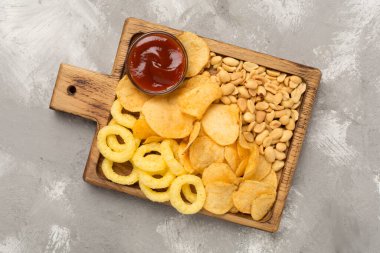 Beton arka planda lezzetli atıştırmalıklar olan tahta, üst görünüm