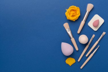 Renk arkaplanında makyaj fırçaları ve süngerler, üst görünüm