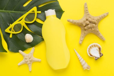 Renk arkaplanında yaz dekoru olan güneş kremi, üst görünüm