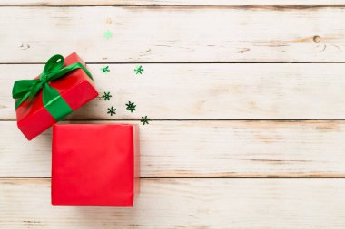 Ahşap arka planda parti konfetisi olan kırmızı hediye kutusunu aç.