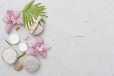 Beton zemin üzerinde orkideler ve masaj taşları olan kompozisyon, üst görünüm