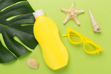 Renk arkaplanında yaz dekoru olan güneş kremi, üst görünüm