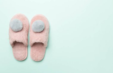 Soft pink slippers on color background, top view