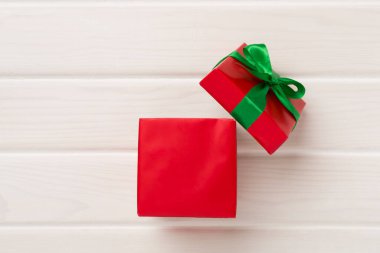 Ahşap arka planda parti konfetisi olan kırmızı hediye kutusunu aç.