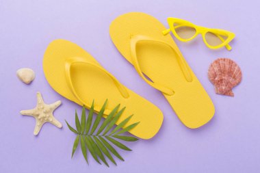 Renkli arka planda parlak sarı parmak arası terlikler, üst manzara. Yaz konsepti