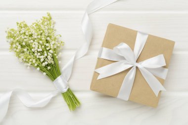 Ahşap arka planda hediye kutusuyla vadideki zambaklar.