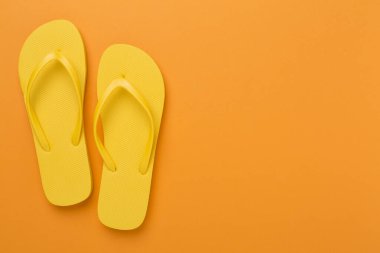 Renkli arka planda parlak sarı parmak arası terlikler, üst manzara. Yaz konsepti