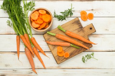 Tahta arka planda dilimlenmiş havuçlarla dolu taze havuçlar.