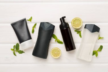 Ahşap arka planda nane yapraklı erkekler kozmetik şişeleri, üst manzara.