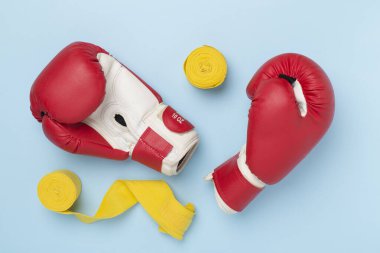 Red boxing gloves on color background, top view.