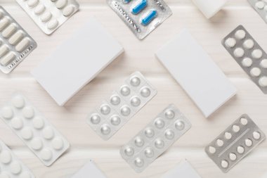 Su toplamada ve kutularda farklı haplar ve ahşap arka planda üst görünüm.