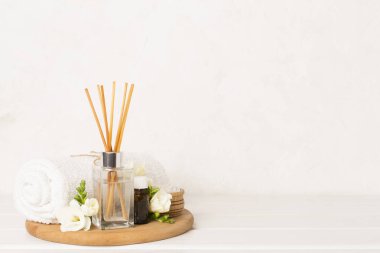 Tahta masa üzerinde frezya çiçeği ve aroma yayıcı içeren spa kompozisyonu