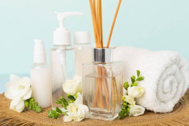 Tahta masa üzerinde frezya çiçeği ve aroma yayıcı içeren spa kompozisyonu