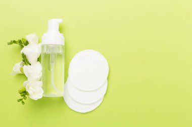 Renkli arka planda frezya çiçekleri olan kozmetik şişeleri, üst görünüm