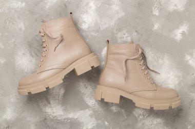 Beton arka planda bej renkli moda çizmeler, üst görünüm.