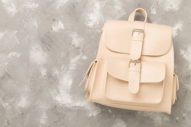 Beton zemin üzerinde bej renkli stil sırt çantası, üst görünüm.