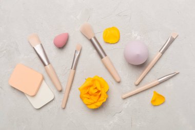 Beton arka planda makyaj fırçaları ve süngerler, üst görünüm