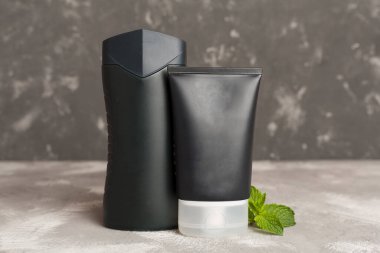 Erkekler, arka planda nane yapraklı kozmetik şişeleri.