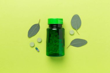 İlaç şişesi ve yeşil yapraklı arka plan, üst görünüm