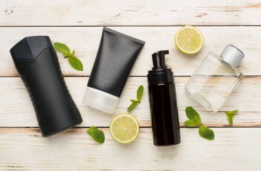 Ahşap arka planda nane yapraklı erkekler kozmetik şişeleri, üst manzara.