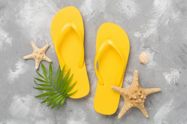 Beton arka planda parlak sarı parmak arası terlikler, üst manzara. Yaz konsepti