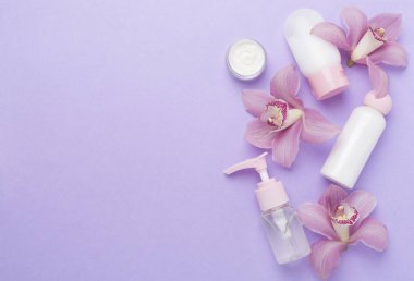 Orkideli kompozisyon, renk arkaplanlı spa ürünleri, üst görünüm