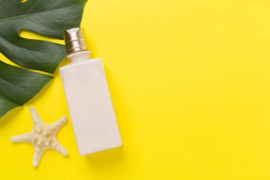 Renk arkaplanında yaz dekoru olan güneş kremi, üst görünüm