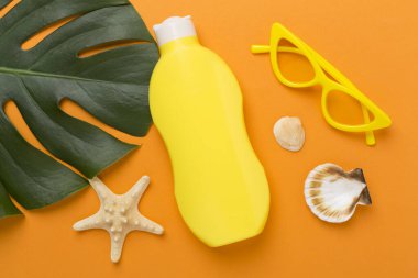 Renk arkaplanında yaz dekoru olan güneş kremi, üst görünüm