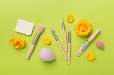 Renk arkaplanında makyaj fırçaları ve süngerler, üst görünüm