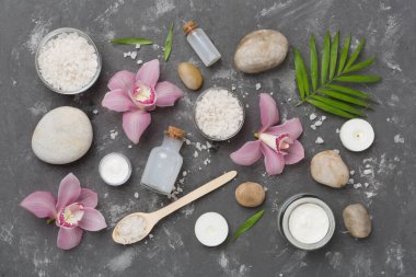 Beton zemin üzerinde orkideler ve masaj taşları olan kompozisyon, üst görünüm